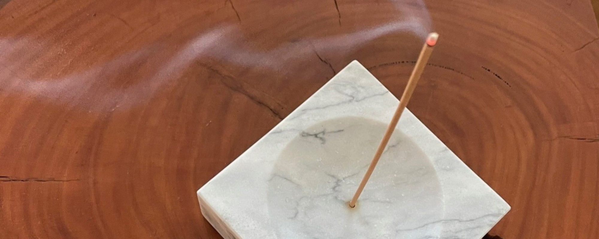 A marble incense holder  with lit incense on rich wooden table