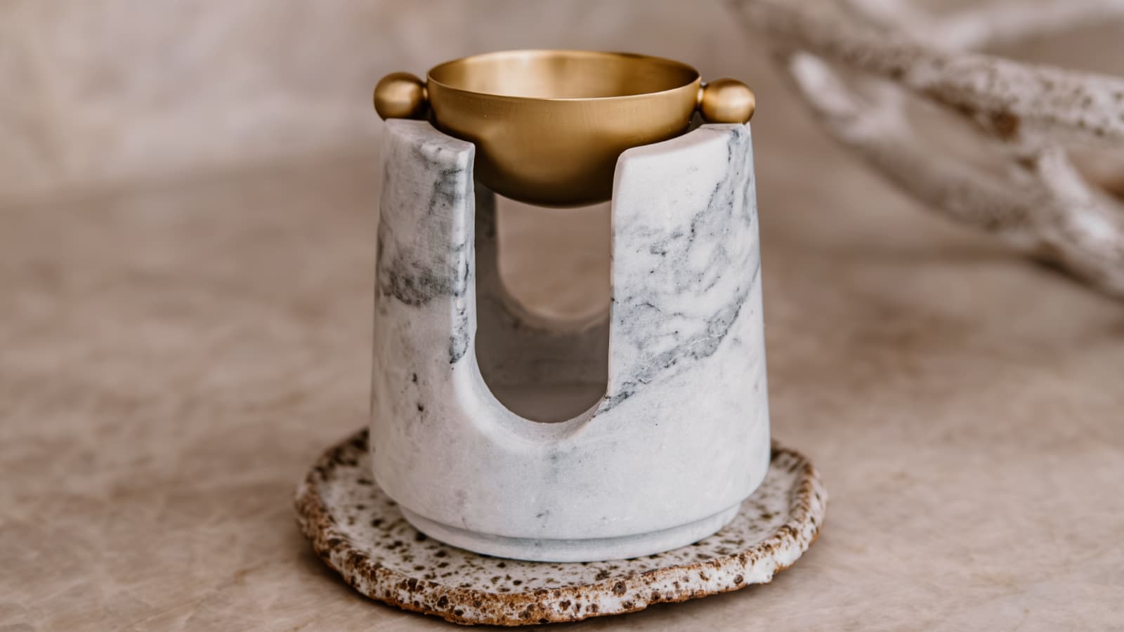 a marble and brass oil burner in neutral setting